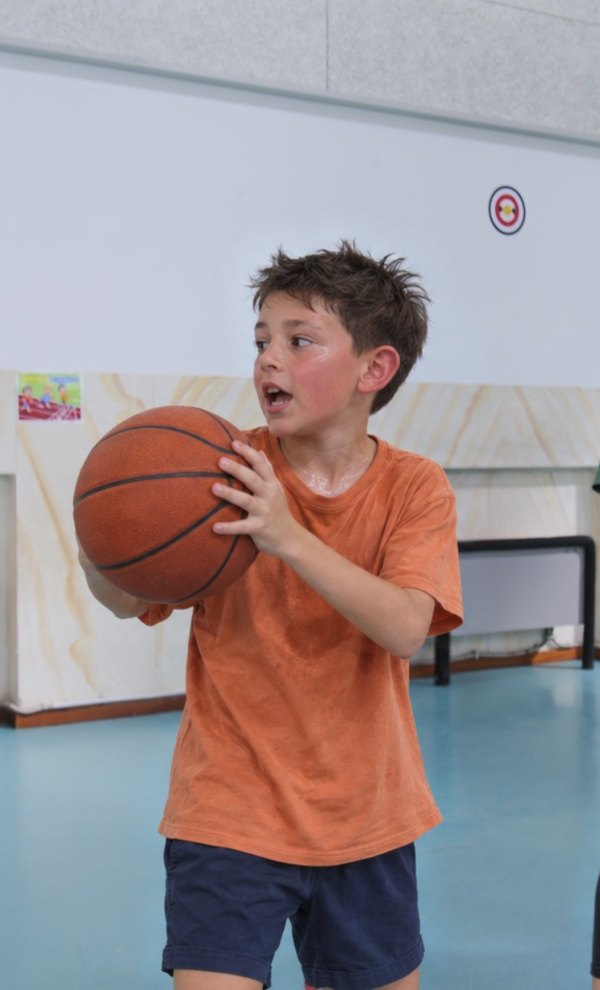 Bambino con il pallone da basket in palestra