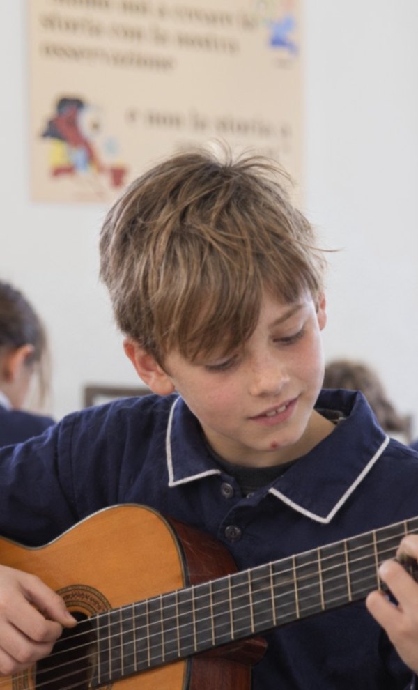 Bambino che suona la chitarra durante la lezione di strumento