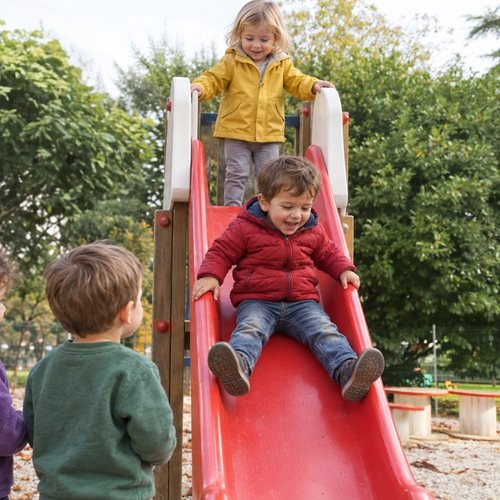 Bambini sullo scivolo nel giardino della scuola