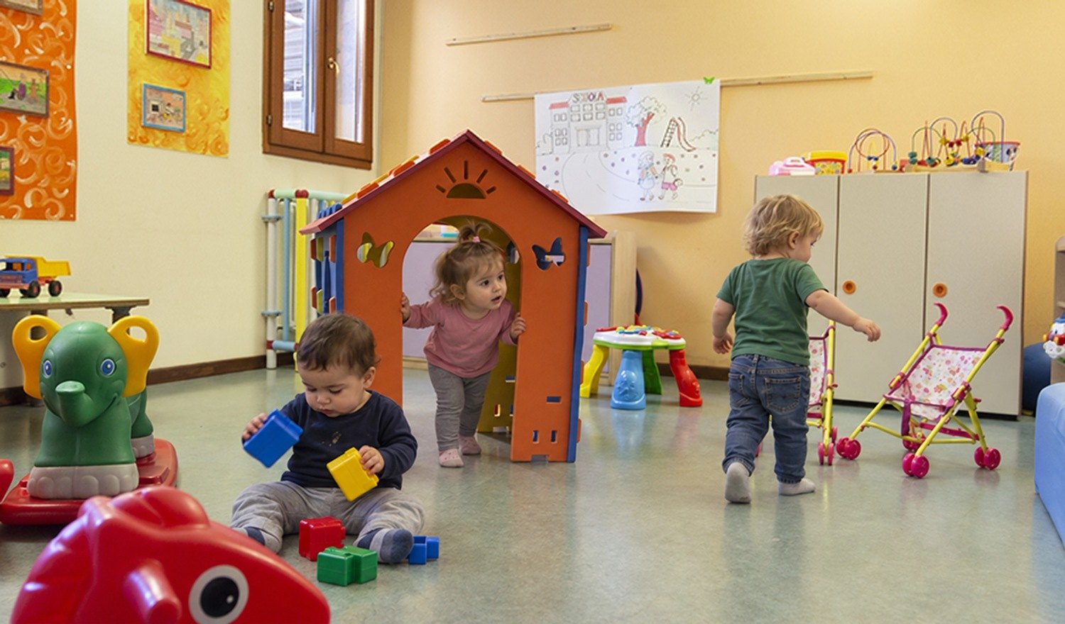 Bambini del nido che giocano intorno alla casetta nella sala gioco