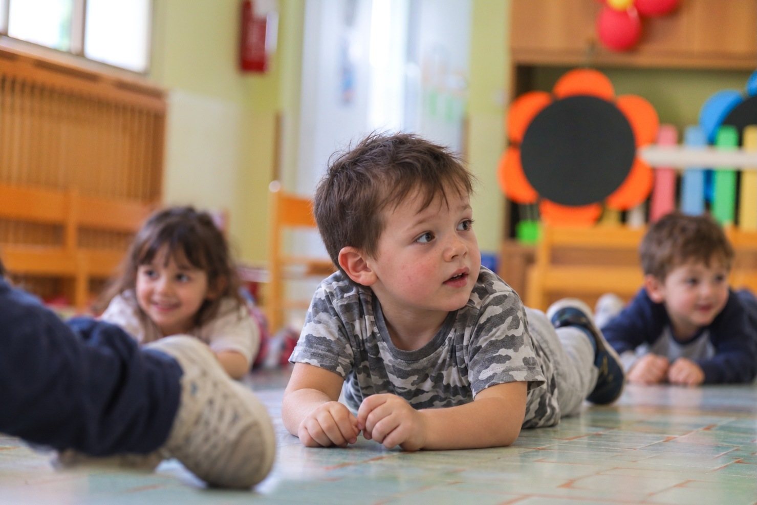 Bambini dell’infanzia sdraiati a terra durante un gioco in palestra