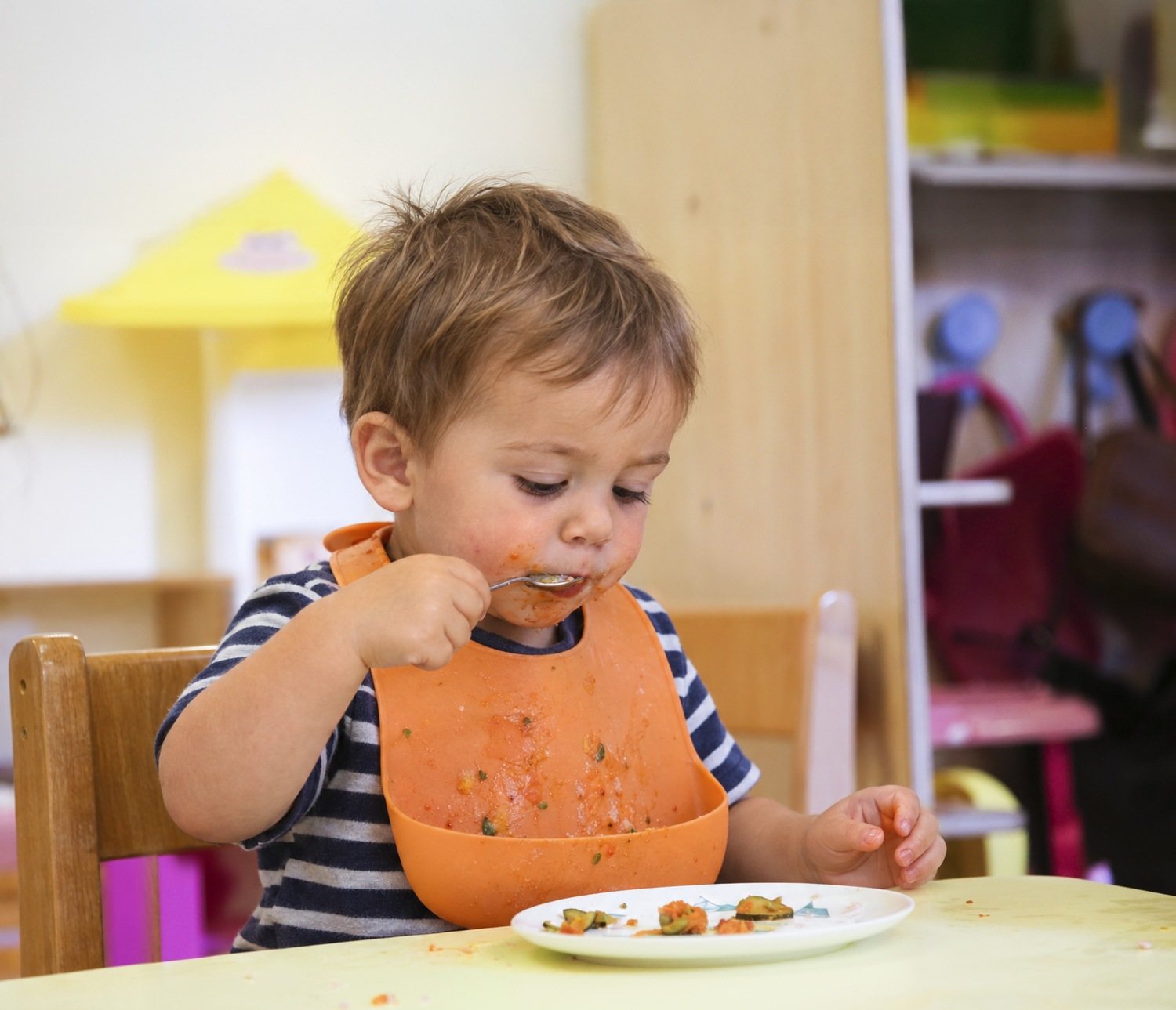Un bimbo del nido che mangia da solo con il cucchiaino
